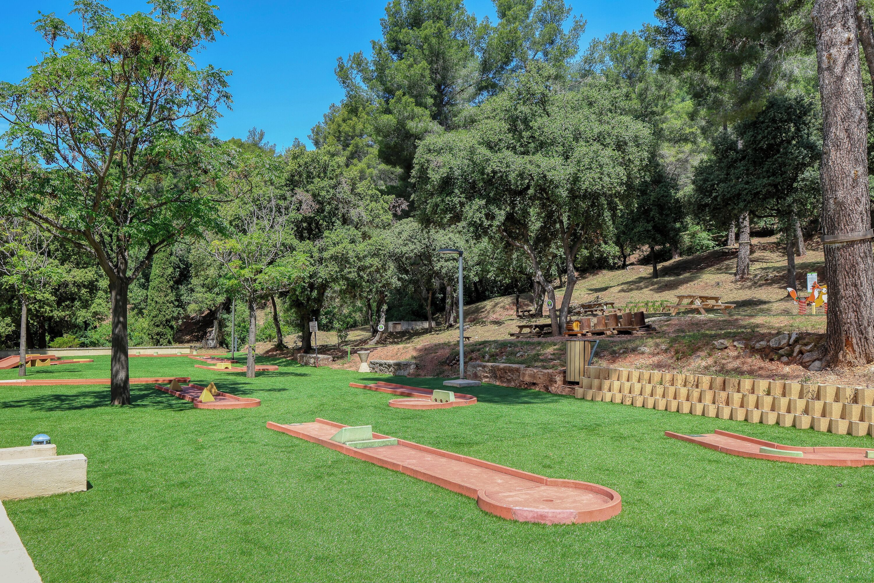 Un parc bien entretenu, avec de l’herbe verte, des arbres et une petite piste rouge.