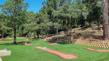 Un parc bien entretenu, avec de l’herbe verte, des arbres et une petite piste rouge.