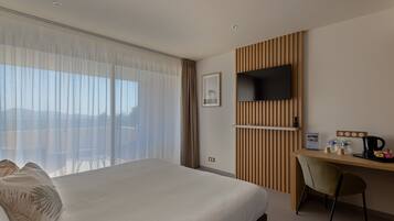 Une chambre d’hôtel dotée d’un grand lit, d’un bureau avec un téléviseur à écran plat, d’une chaise et offrant une vue sur l’extérieur.