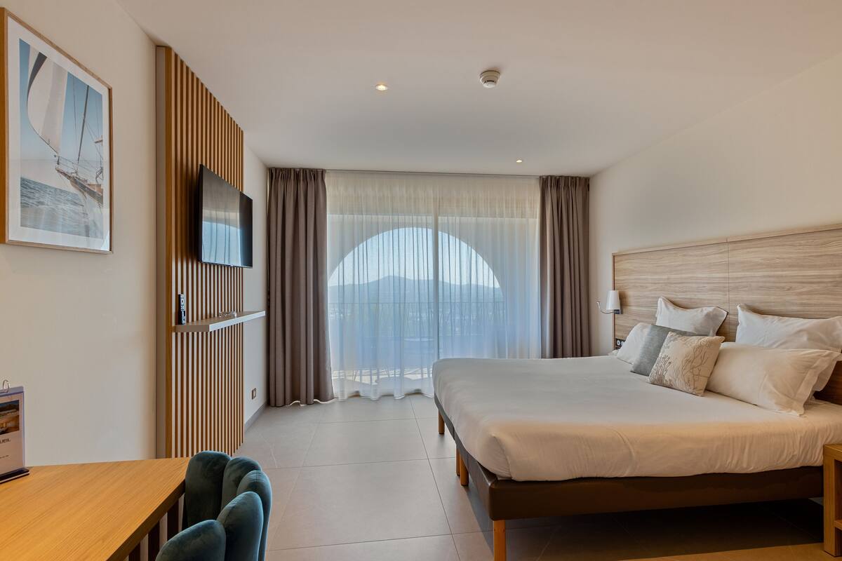 Ein modernes Hotelzimmer mit einem großen Bett, einem Schreibtisch und einem Fernseher.