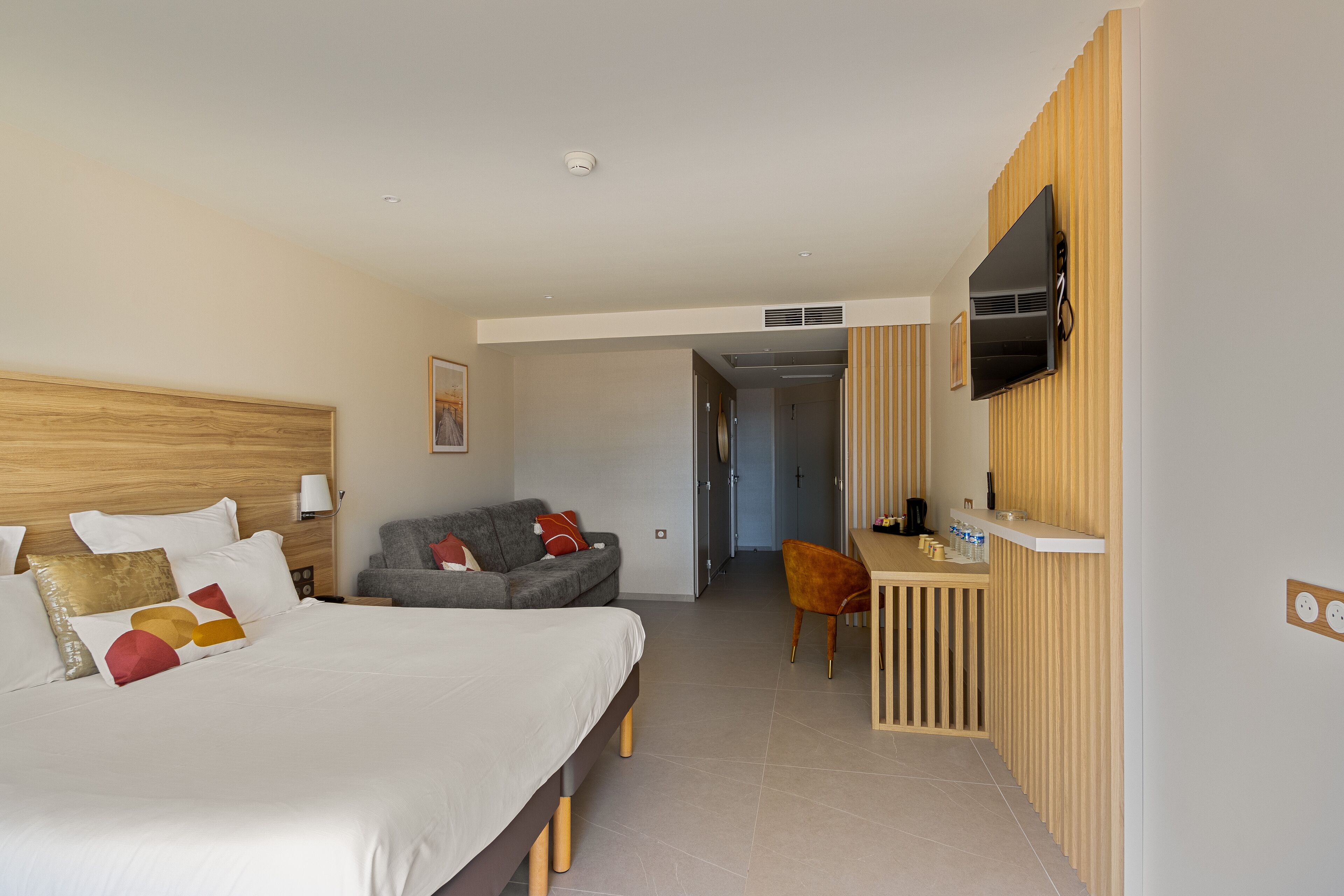 Hotellihuone, jossa on sänky, työpöytä, televisio ja sohva.