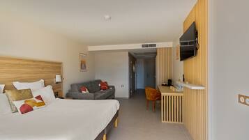 A hotel room with a bed, a desk, a TV, and a sofa.