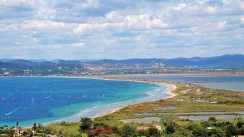 A coastal landscape with a beach, boats, and a distant town.