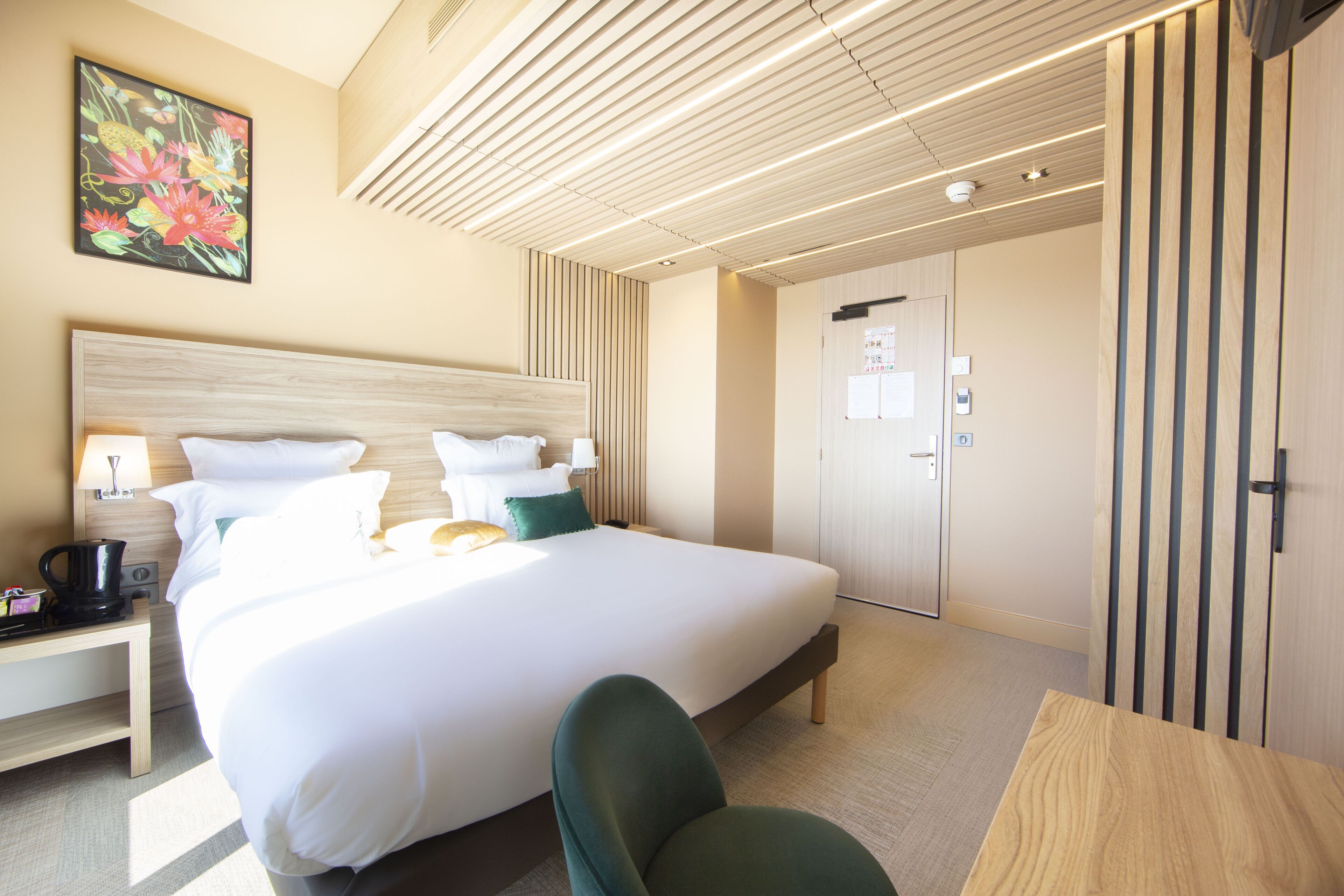 A hotel room with a large bed, bedside tables, a desk, and a wardrobe.