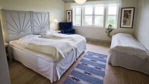 Un dormitorio con una cama grande, una cama más pequeña, una silla y una ventana con vistas.