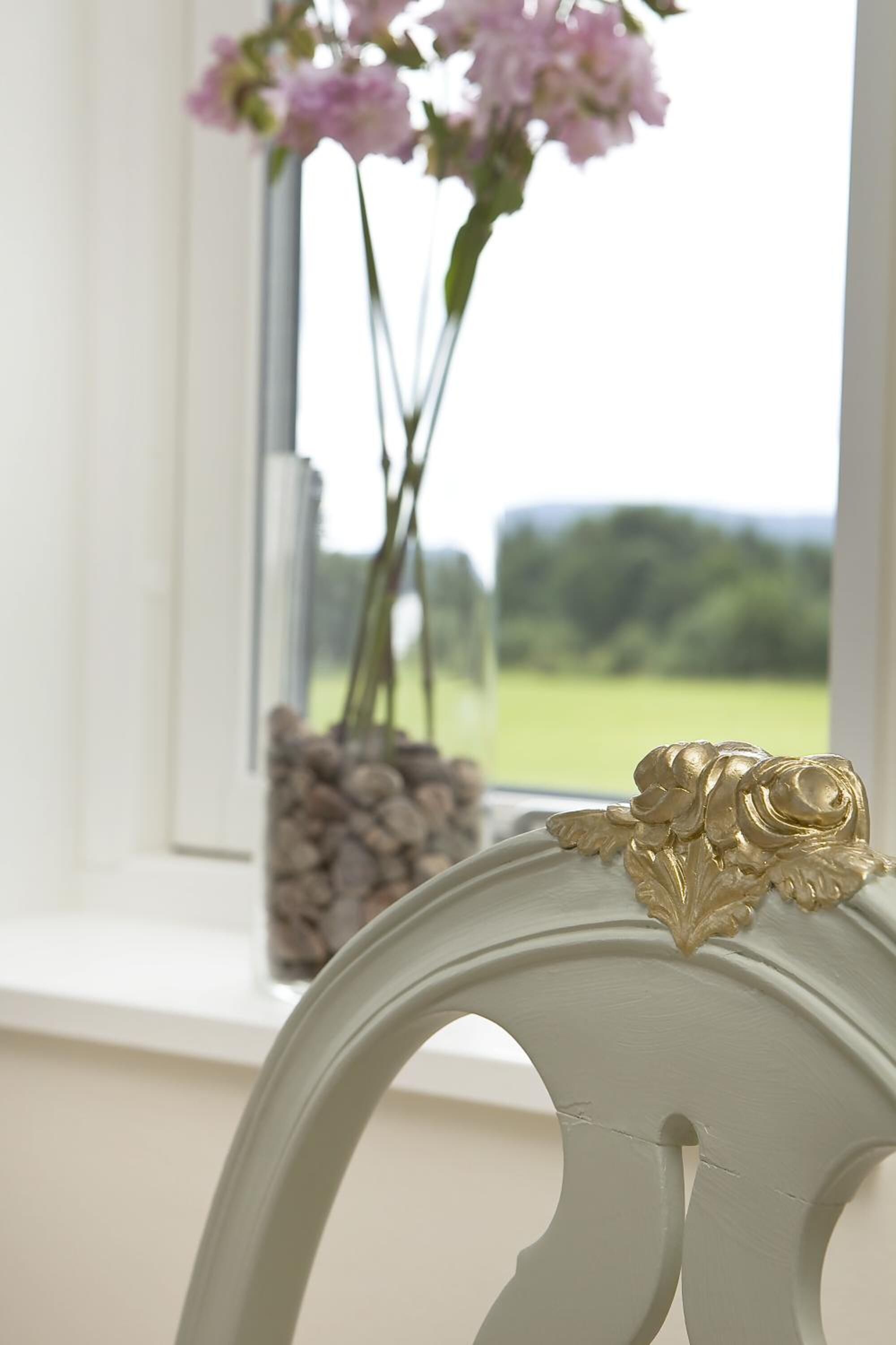 Ein Fenster mit Blumen in einer Vase und einem Holzstapel.
