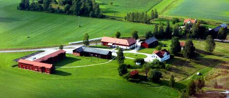 A rural landscape with a large barn, smaller buildings, and a field.