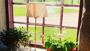 Una mesa con una lámpara, plantas en macetas y copas de vino cerca de una ventana que da a un campo de golf.