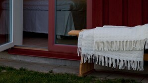 Una habitación con cama, banco y ventana con vistas al cielo.