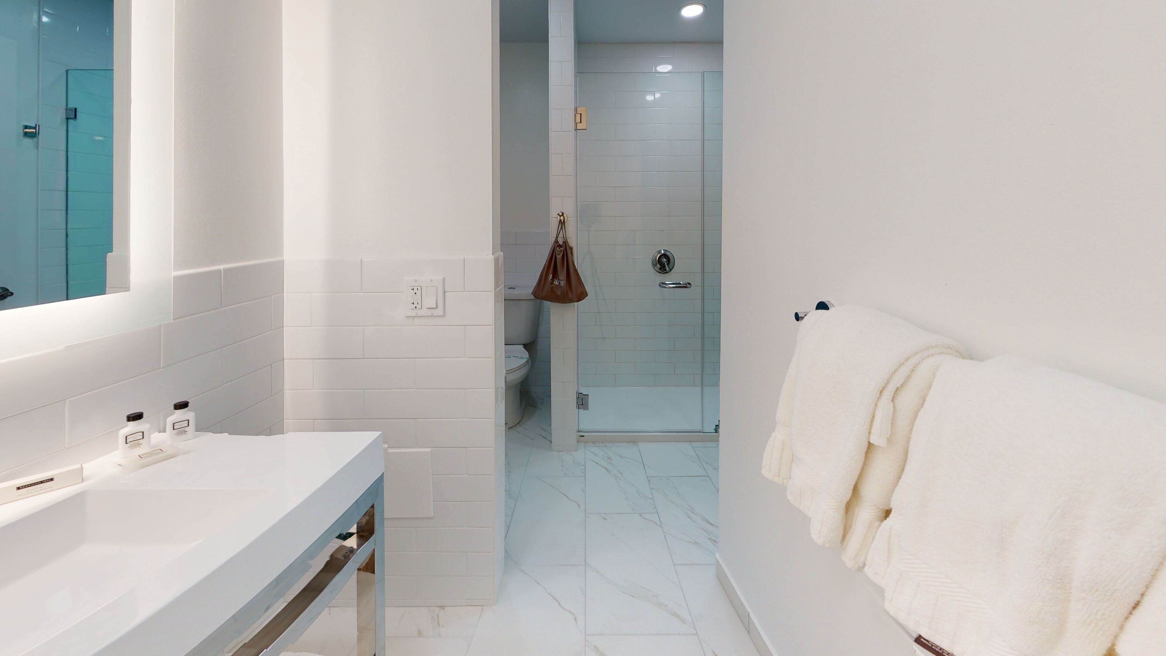Une salle de bain moderne avec un meuble-lavabo blanc, une cabine de douche en verre et un porte-serviettes.