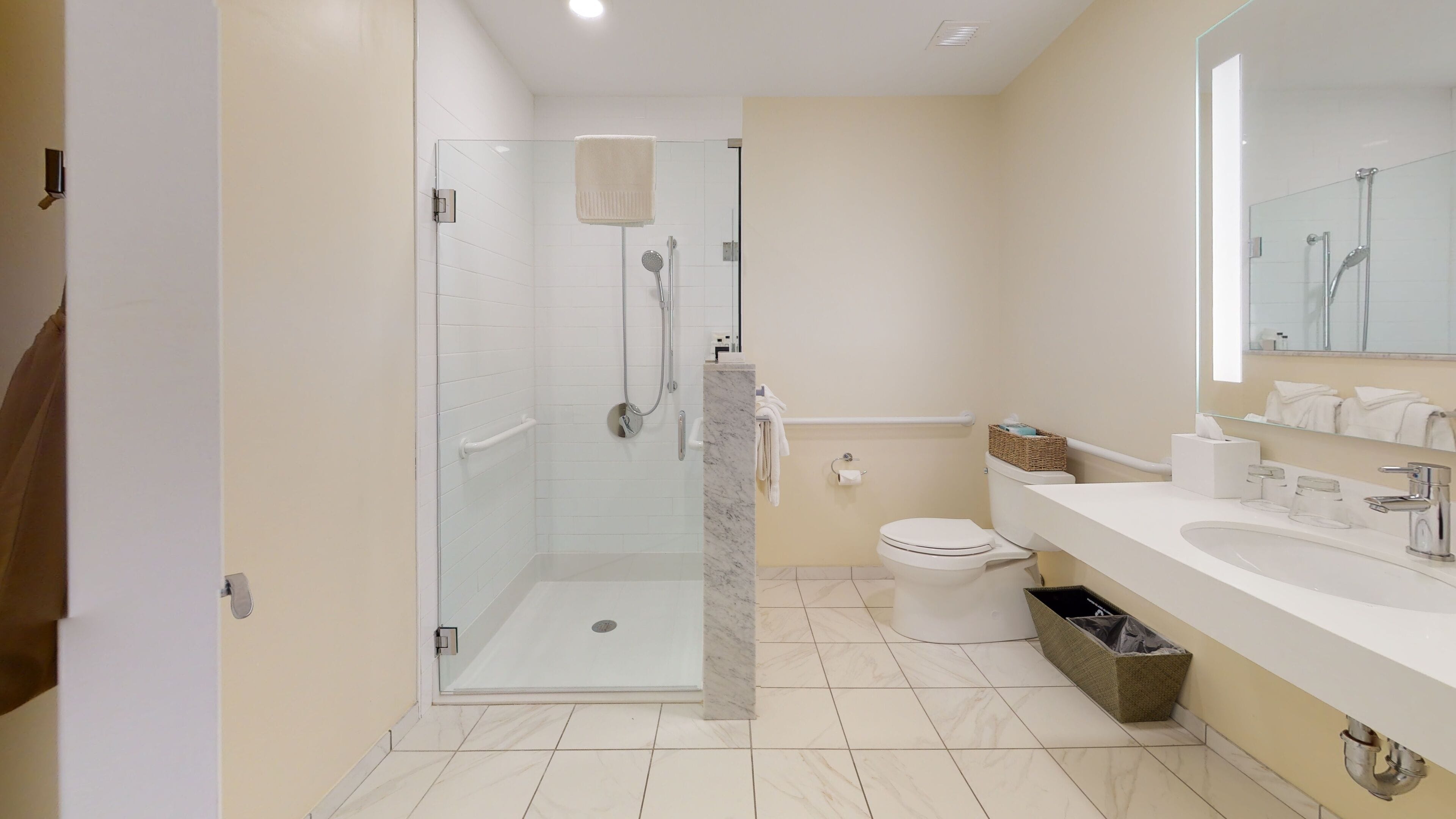 A modern bathroom with a glass-enclosed shower, a toilet, and a vanity with a mirror.