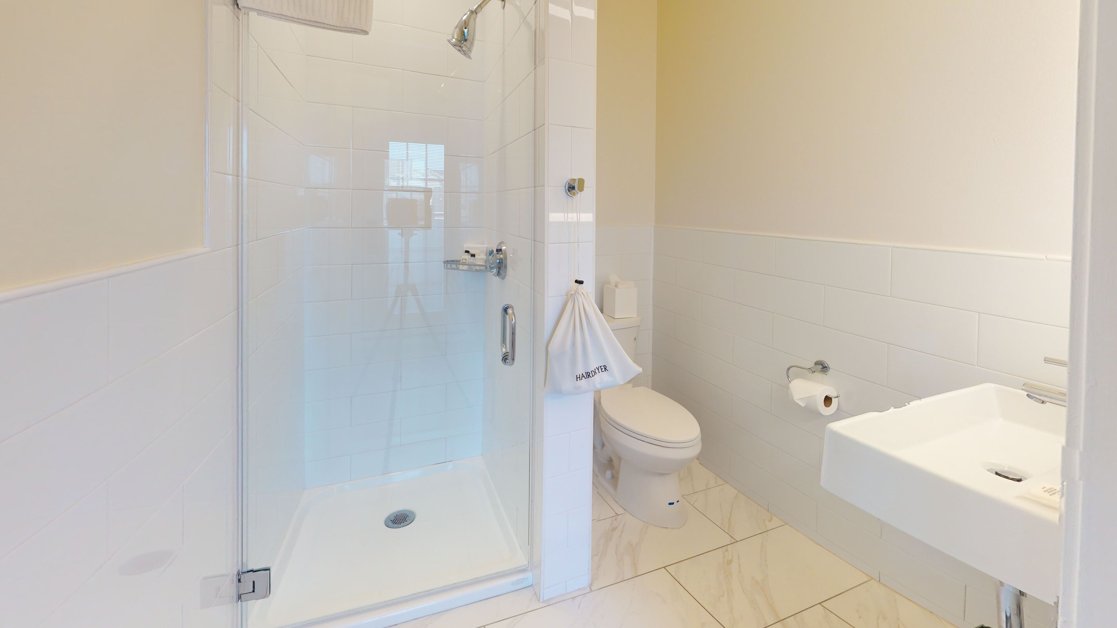 A modern bathroom with a glass-enclosed shower, a toilet, and a sink.