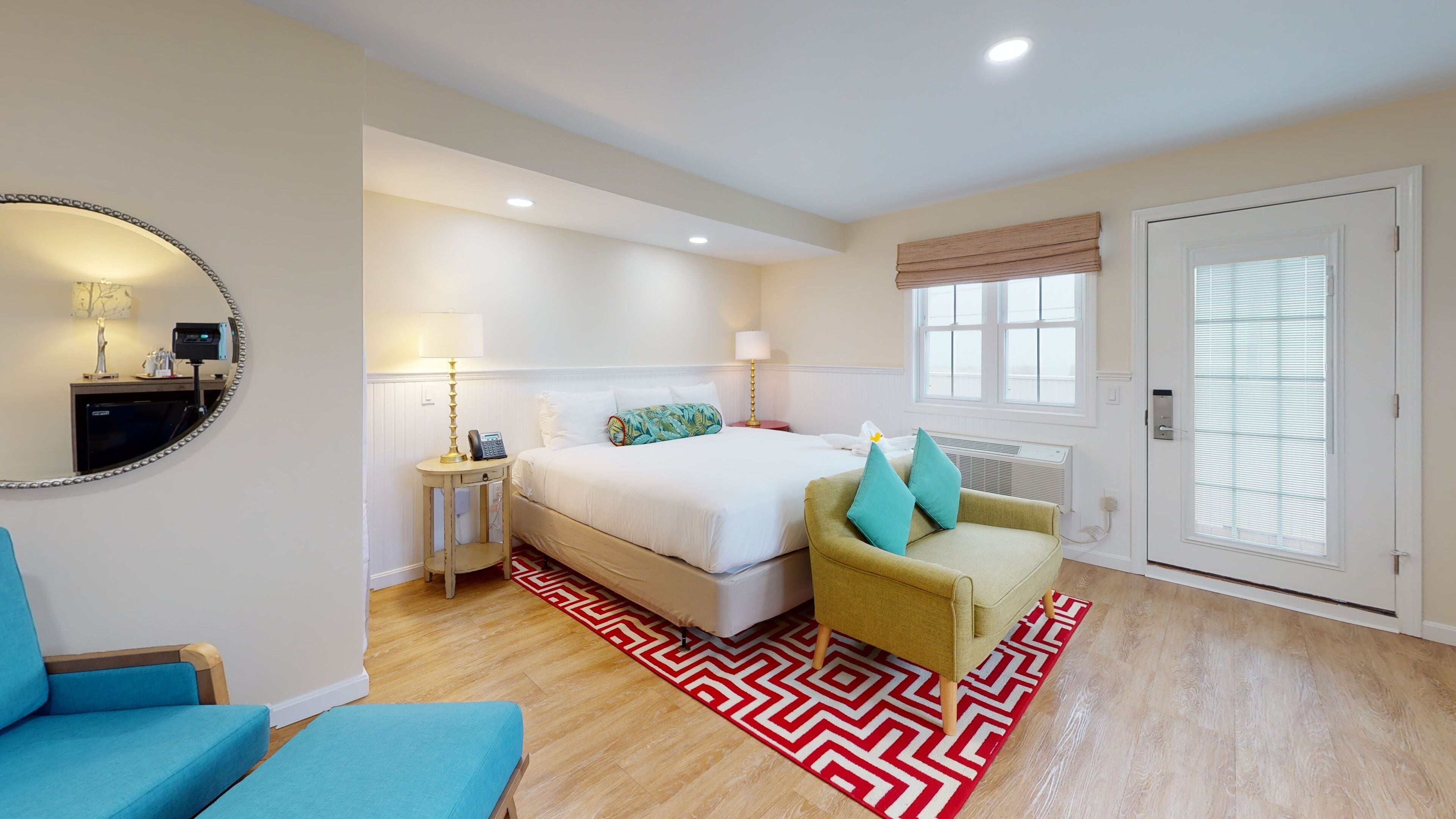 A hotel room with a bed, bedside tables, a chair, a mirror, and a window.