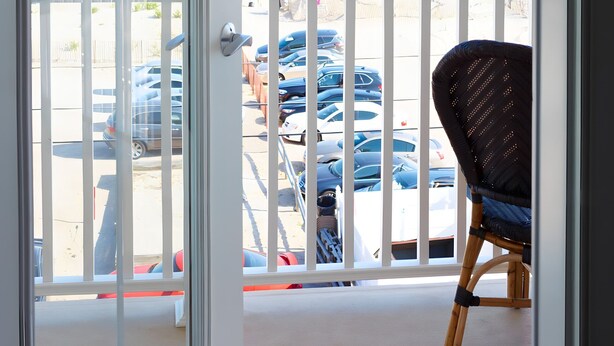 A balcony with a view of the ocean and parked cars. - The Hotel Maria (Westerly)