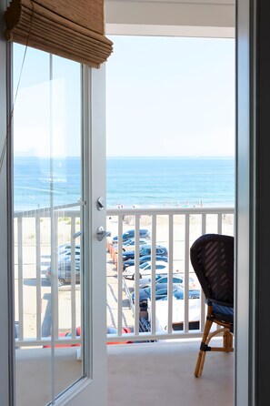 A balcony with a view of the ocean and parked cars. - The Hotel Maria (Westerly)