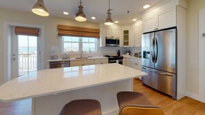 A modern kitchen with a large island, stainless steel appliances, and pendant lighting. - The Hotel Maria (Westerly)