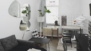 Una habitación moderna y compacta con sofá, mesa de comedor y radiador.