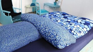 Un dormitorio con cama, escritorio, silla, lámpara colgante y una obra de arte en la pared.