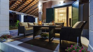 An outdoor patio with wicker furniture, a table, and potted plants. - Villa Rusula (Kastela)