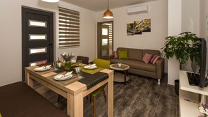 A modern living room with a dining area, a sofa, a coffee table, and a TV on a stand. - Villa Rusula (Kastela)