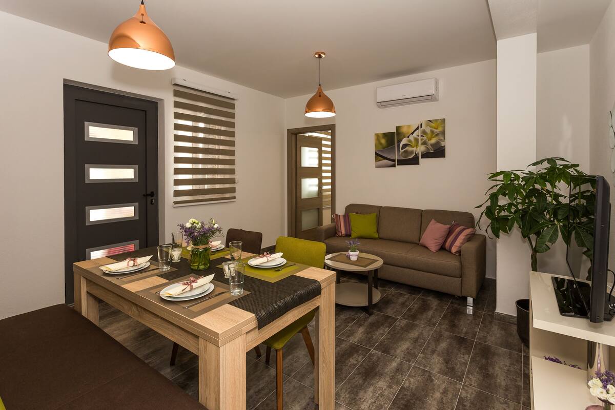 A modern living room with a dining area, a sofa, a coffee table, and a TV on a stand.