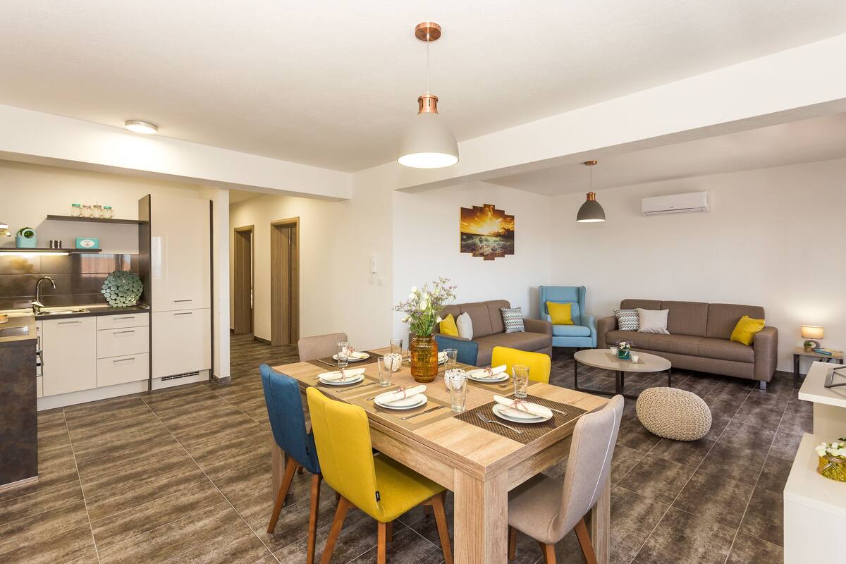 A modern living space with a dining area, kitchen, and seating area.
