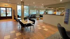 A spacious indoor area with a reception desk, seating arrangements, and large windows providing views of the outside. - Marina Hotel Lofoten (Vagan)
