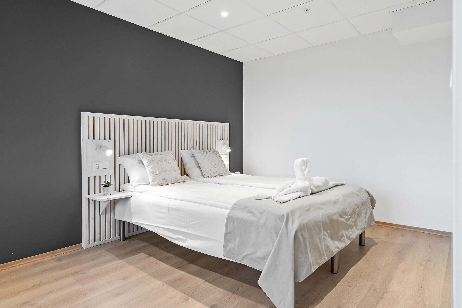 Un dormitorio moderno con cama, mesitas de noche y una mesita auxiliar.