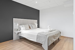 Een moderne slaapkamer met een bed, nachtkastjes en een bijzetmeubel.