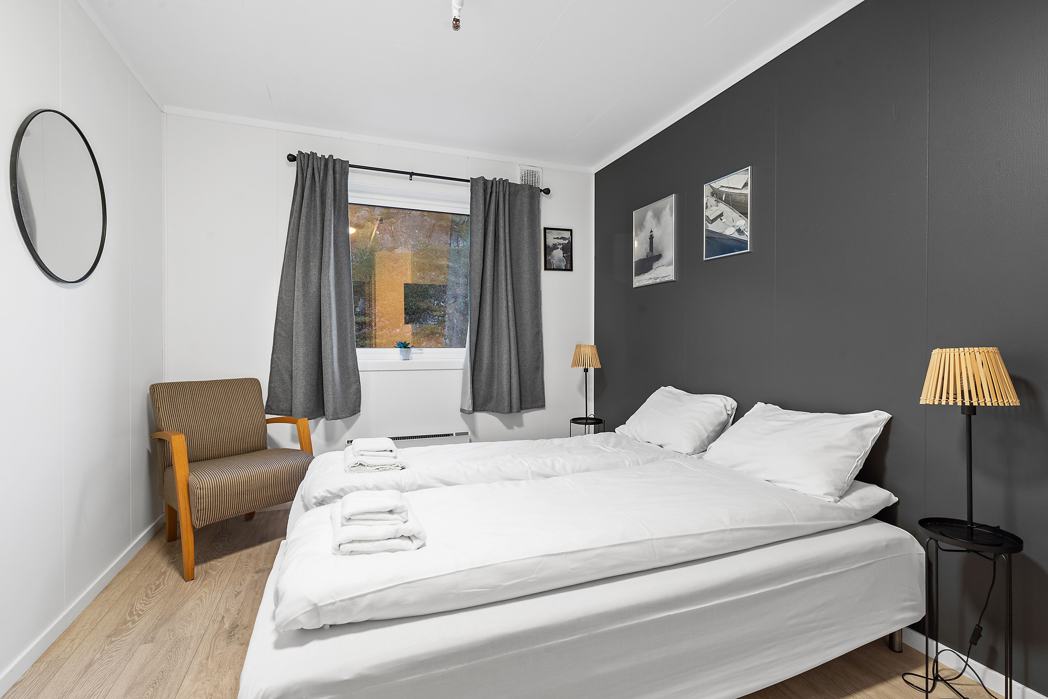 A bedroom with a bed, a chair, a lamp, and a window with curtains.
