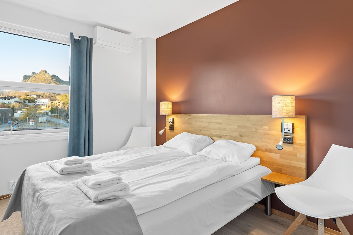 Ein Hotelzimmer mit Bett, einem Sessel und Bergblick.