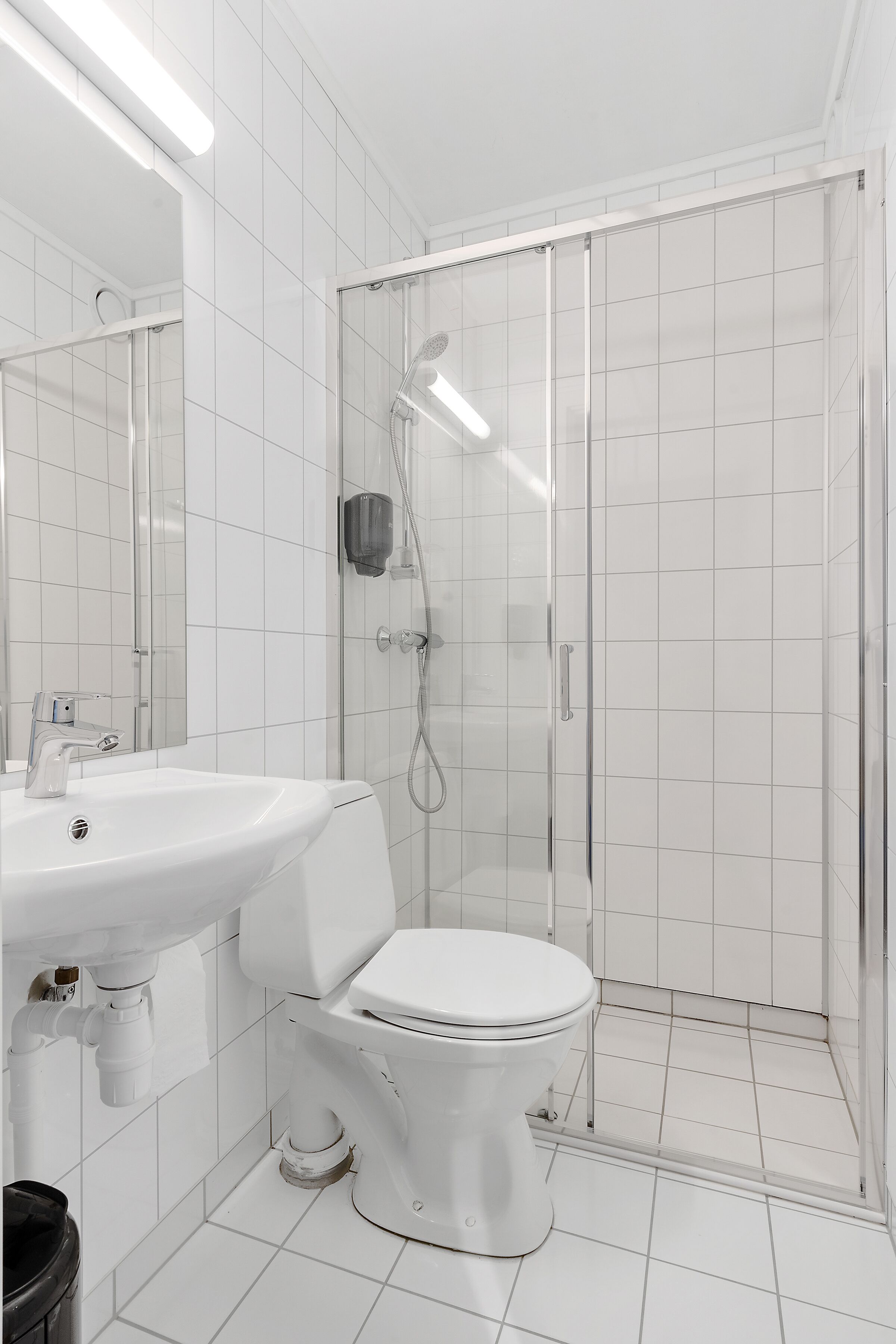 Casa de banho moderna com lavatório branco, sanita e cabine de duche em vidro.