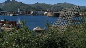 A coastal town with a marina, boats, and a mountain backdrop. - Marina Hotel Lofoten (Vagan)