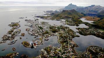 An aerial view of a coastal town with numerous docks and boats, surrounded by mountains and a large body of water.