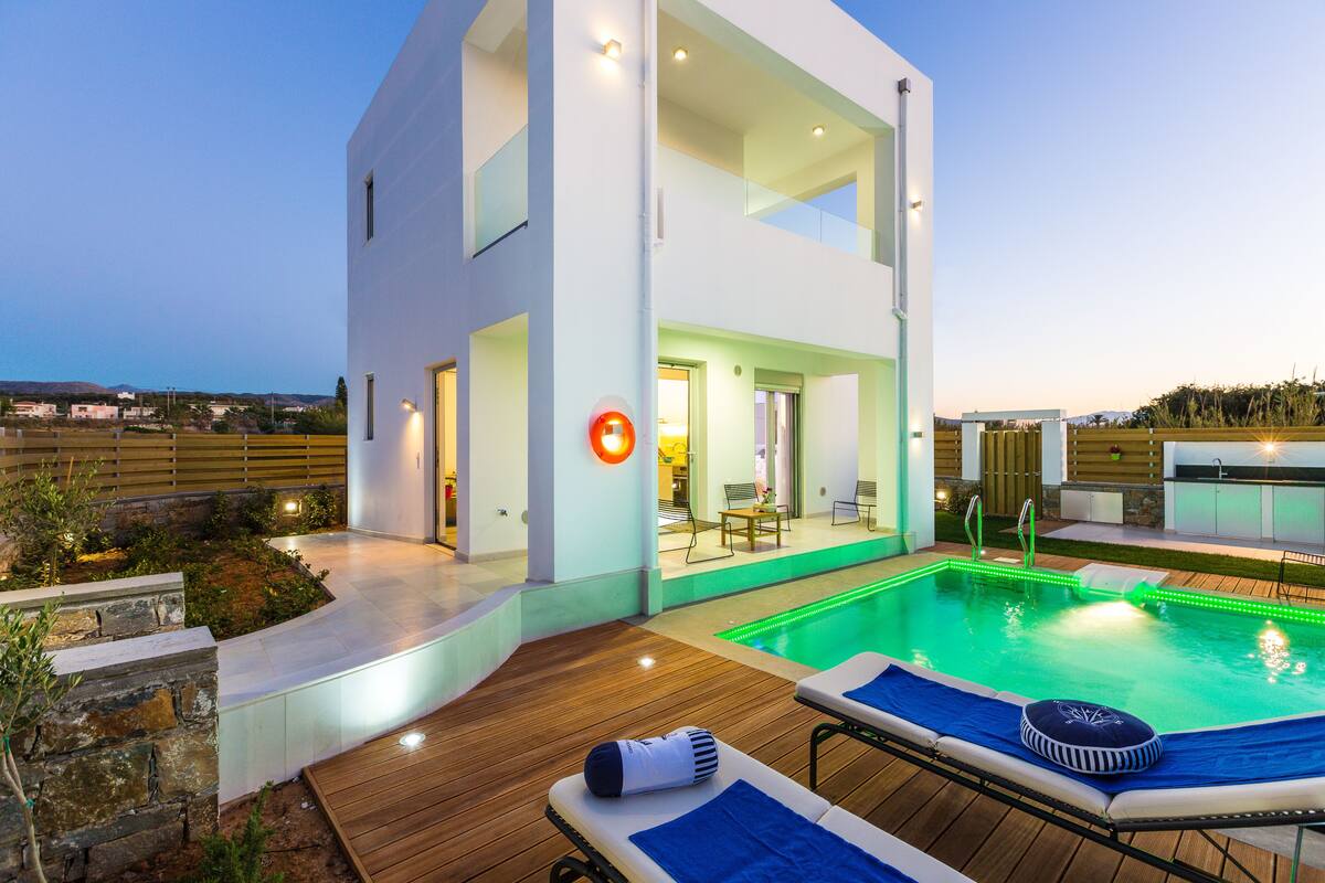 A modern house with a swimming pool, outdoor seating, and a view of the landscape.