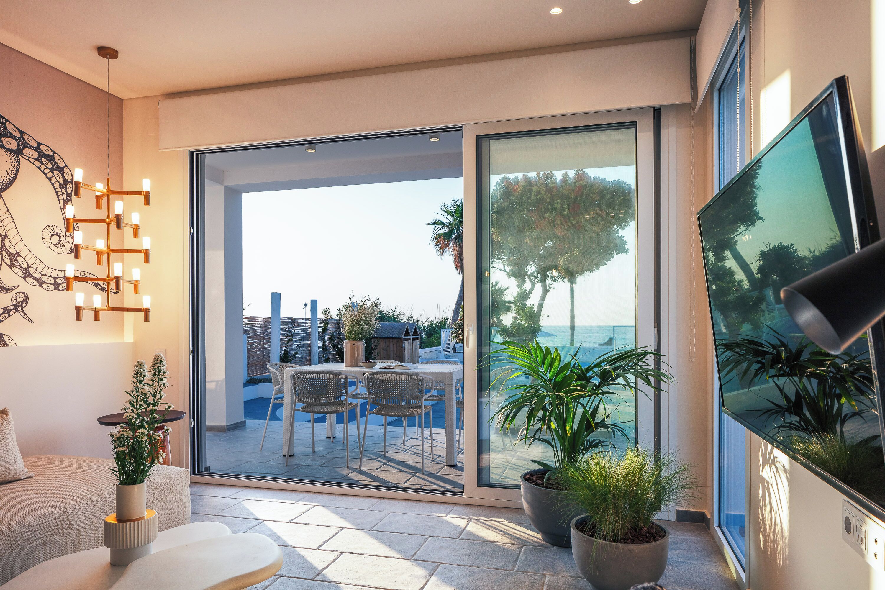 Una sala de estar moderna con un amplio ventanal corredero que da a un patio exterior.