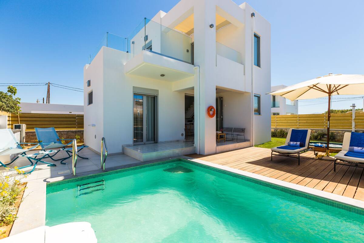 A modern two-story house with a swimming pool, outdoor seating, and a deck.
