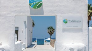 A white-walled building with a sign reading "thalasses living unlimited" and a view of the sea. - Thalasses Villas Rethymno (Rethymno)