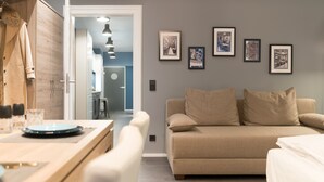 A modern living room with a beige sofa, a wooden dining table, and framed pictures on the wall. - Aparthotel by dasPaul (Nuremberg)