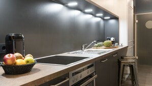 A modern kitchen with a wooden countertop, stainless steel appliances, and a fruit basket. - Aparthotel by dasPaul (Nuremberg)