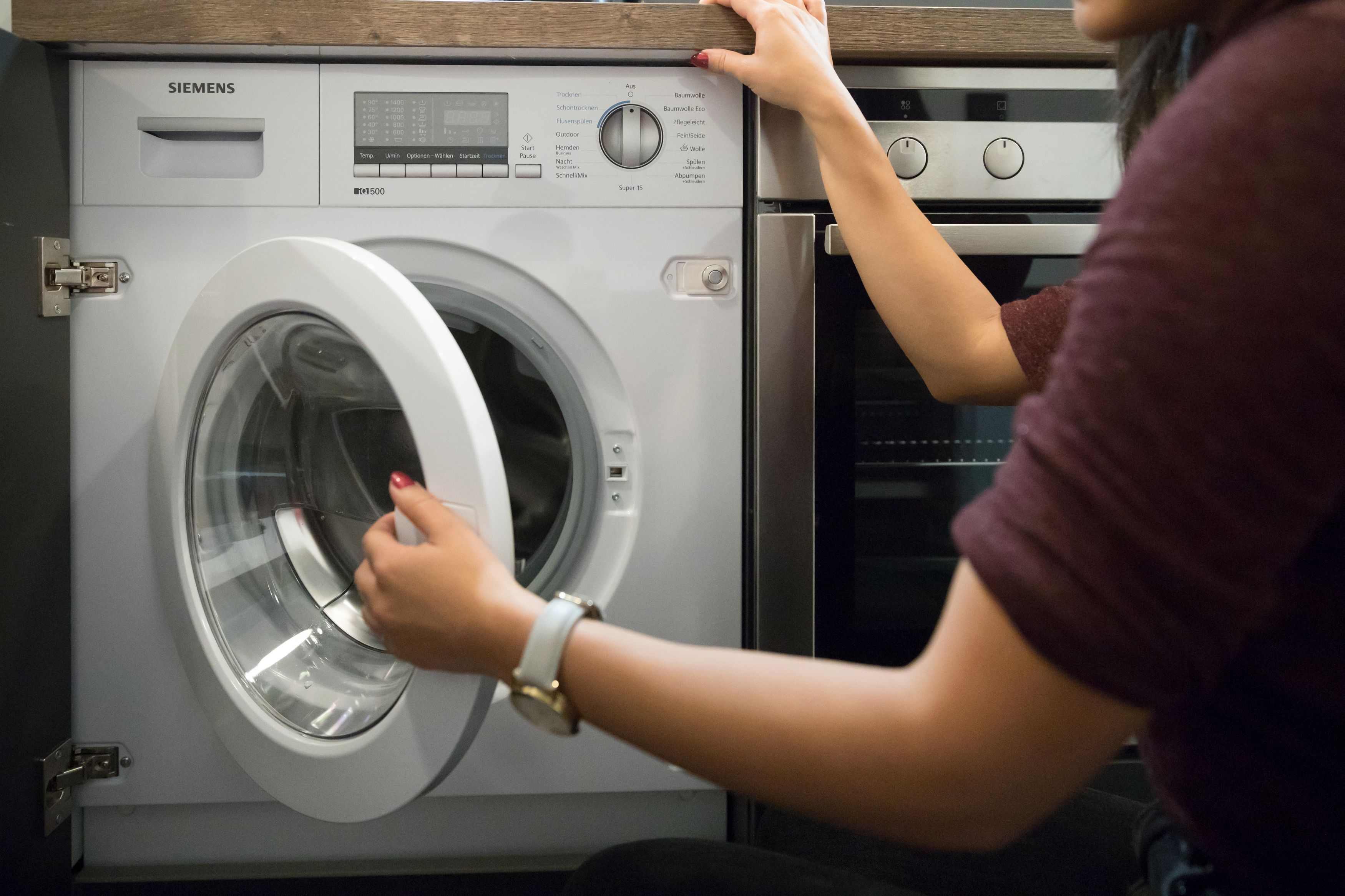 A front-loading washing machine with a control panel and a digital display.