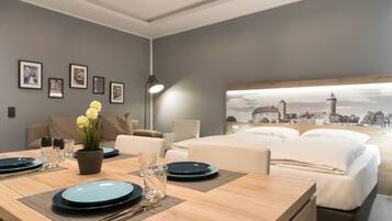 A modern hotel room with a dining area, a bed with a cityscape mural, and framed pictures on the wall.