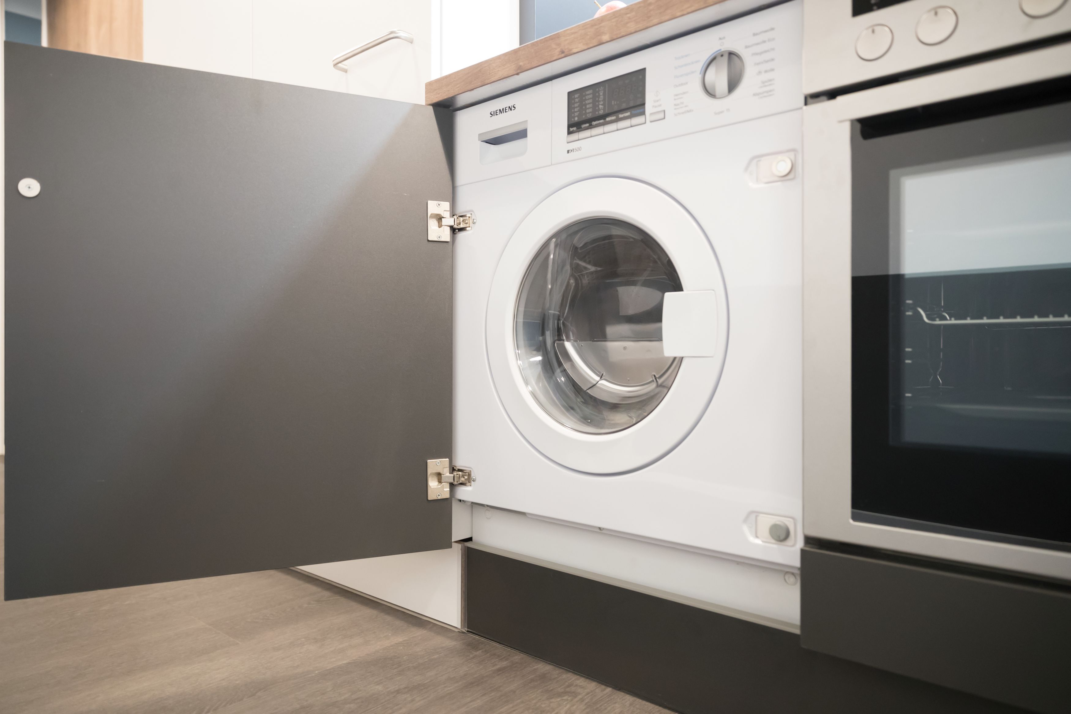 Un moderno lavadero con una lavadora Siemens y un horno empotrado.