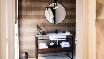 Un bagno moderno con uno specchio rotondo, un lavandino bianco e un mobile contenitore in legno.