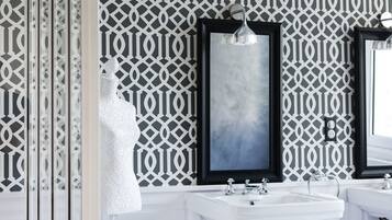 A bathroom with two sinks, a mirror, and a decorative wall with a geometric pattern.
