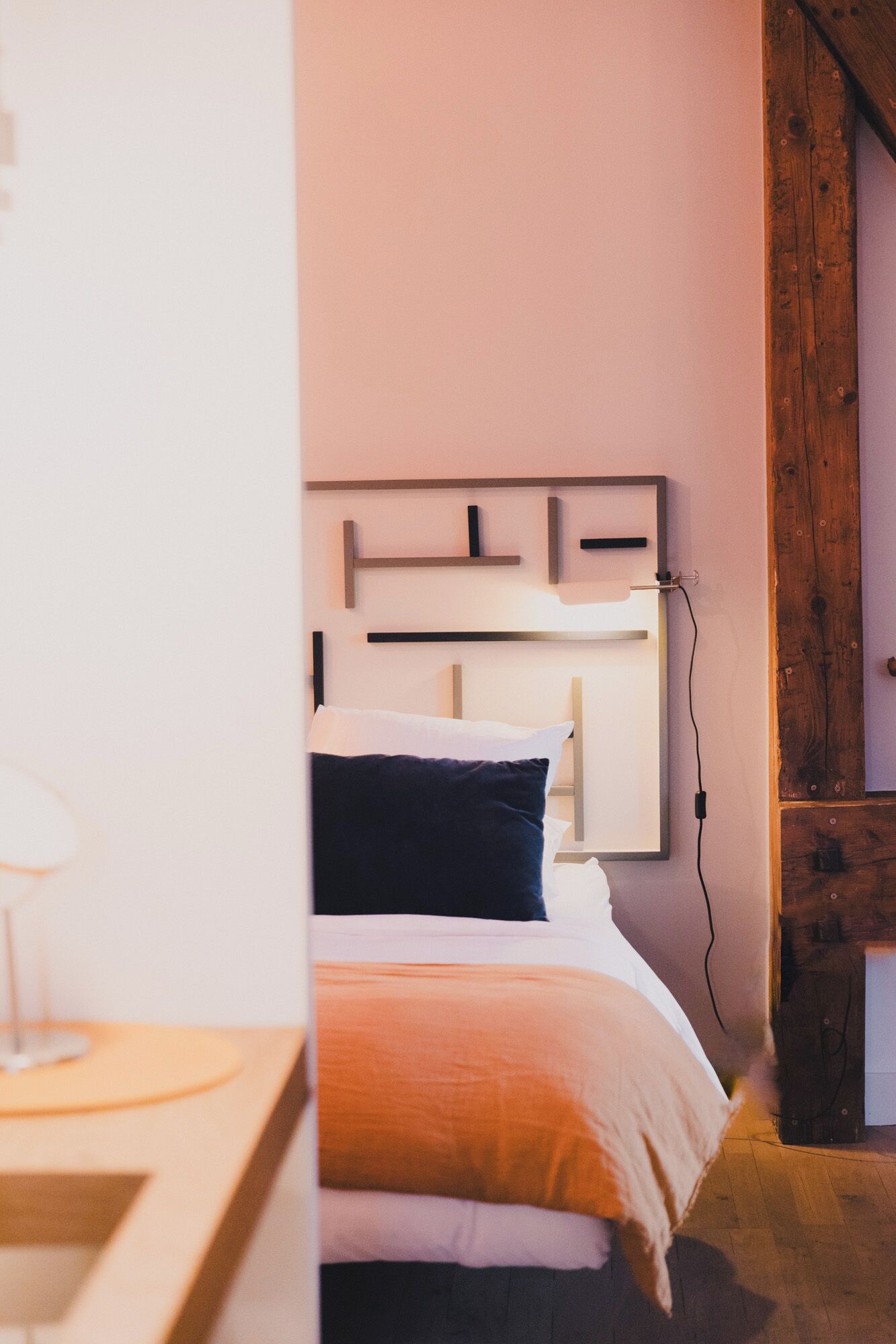 Un dormitorio con cama, mesita de noche y lámpara de pared.
