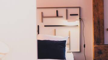 Un dormitorio con cama, mesita de noche y lámpara de pared.