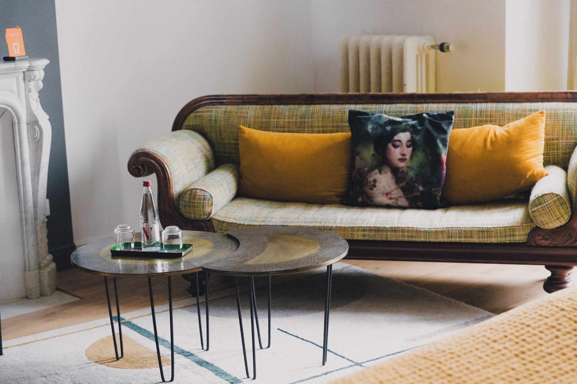 A cozy living room with a sofa, two small round tables, and a decorative pillow.