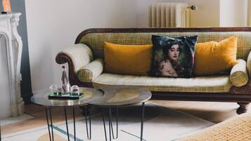 A cozy living room with a sofa, two small round tables, and a decorative pillow.