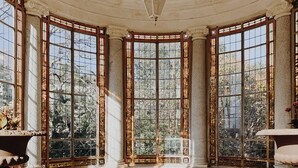 A room with a curved ceiling, large stained glass windows, a central seating area with a sofa and armchairs, and a round ottoman. - La Villa Guy & Spa - Teritoria (Béziers)